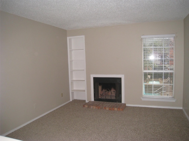 unfurnished living room with carpet floors, built in shelves, and a textured ceiling