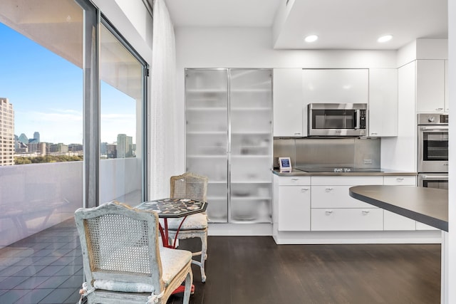 kitchen with dark wood-type flooring, appliances with stainless steel finishes, and white cabinetry