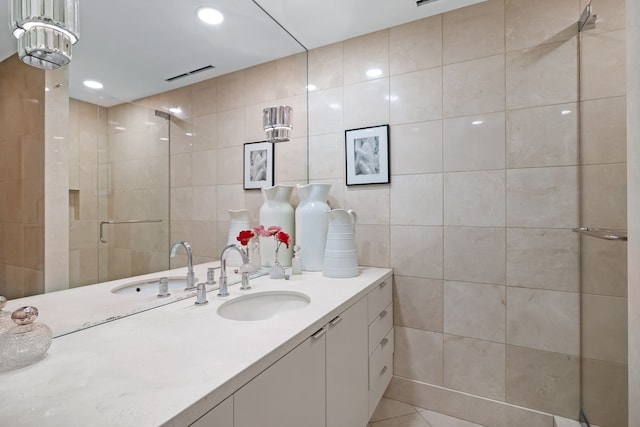 bathroom featuring a shower with shower door, vanity, tile walls, and tile patterned floors