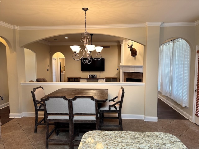 tiled dining room with ornamental molding, arched walkways, a notable chandelier, and baseboards