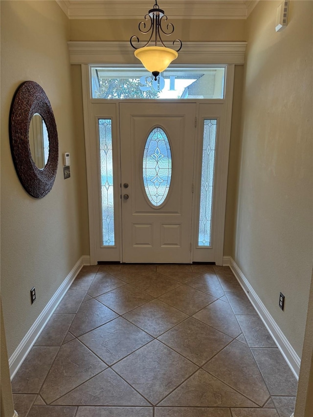 foyer entrance with tile patterned flooring, crown molding, and baseboards