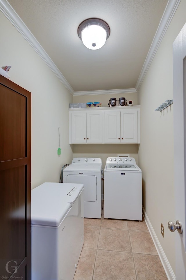 washroom with cabinet space, baseboards, washer and clothes dryer, crown molding, and light tile patterned flooring