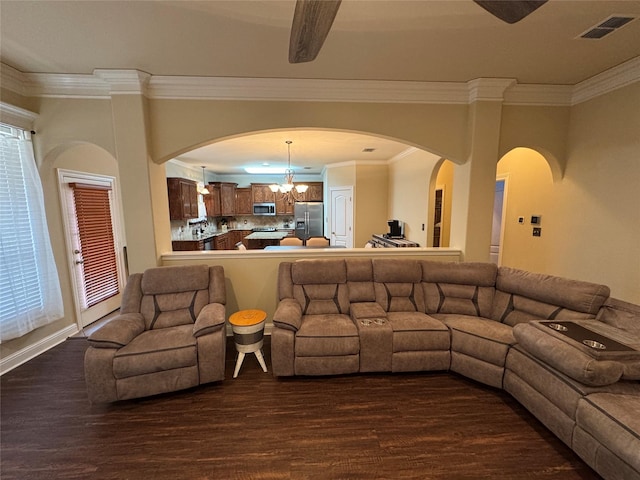 living area featuring dark wood-type flooring, visible vents, a notable chandelier, and crown molding