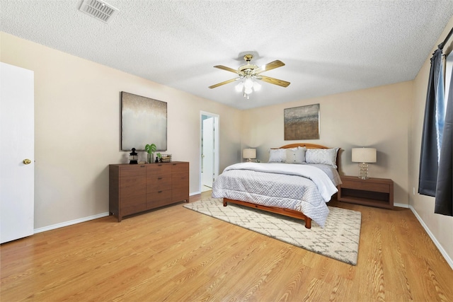 bedroom with a textured ceiling, ceiling fan, and light wood-type flooring