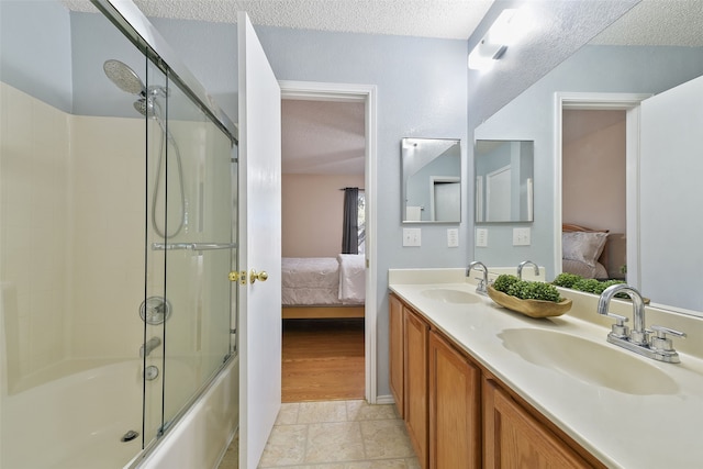 bathroom featuring vanity, combined bath / shower with glass door, and a textured ceiling