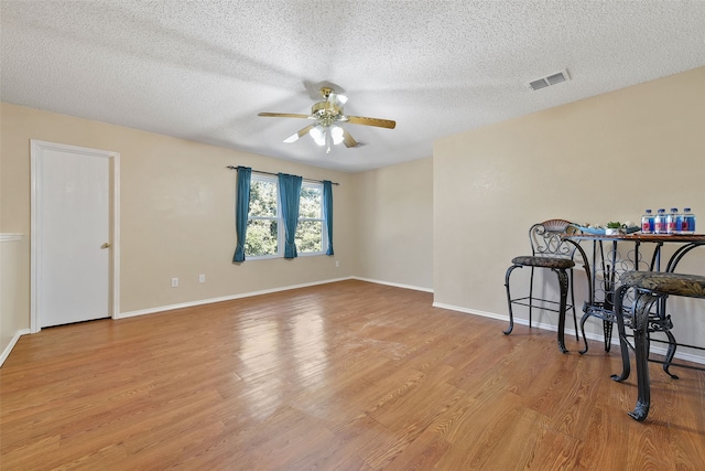 interior space with ceiling fan, a textured ceiling, and light hardwood / wood-style flooring