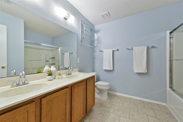 full bathroom with bath / shower combo with glass door, vanity, a textured ceiling, and toilet