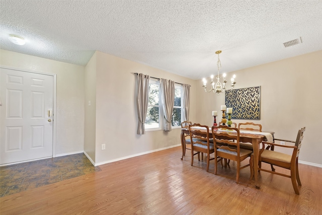 dining room featuring wood-type flooring, a textured ceiling, and a notable chandelier