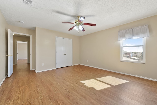 unfurnished bedroom featuring a closet, a textured ceiling, ceiling fan, and light hardwood / wood-style flooring