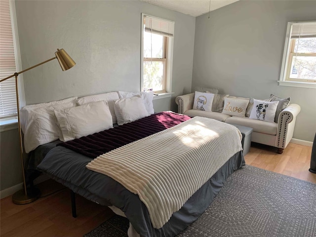 bedroom with light hardwood / wood-style floors and multiple windows