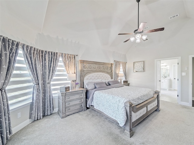 carpeted bedroom with ceiling fan, multiple windows, connected bathroom, and high vaulted ceiling