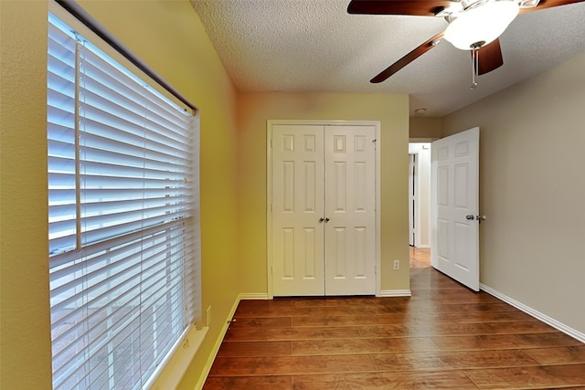 unfurnished bedroom featuring ceiling fan, a closet, a textured ceiling, and hardwood / wood-style floors