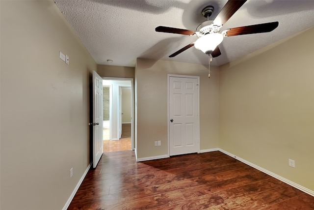 unfurnished bedroom with a textured ceiling, ceiling fan, and dark hardwood / wood-style flooring