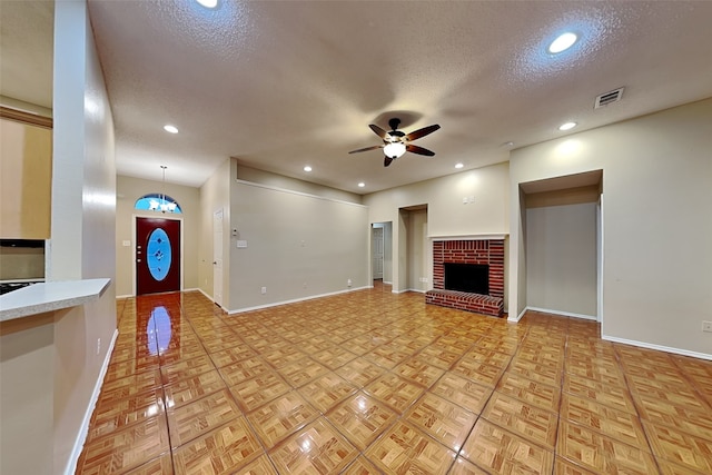 unfurnished living room featuring ceiling fan, light parquet flooring, a fireplace, and a textured ceiling