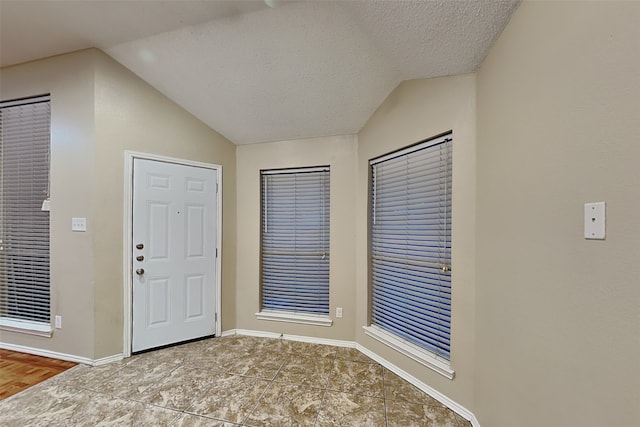 foyer entrance with a textured ceiling and lofted ceiling