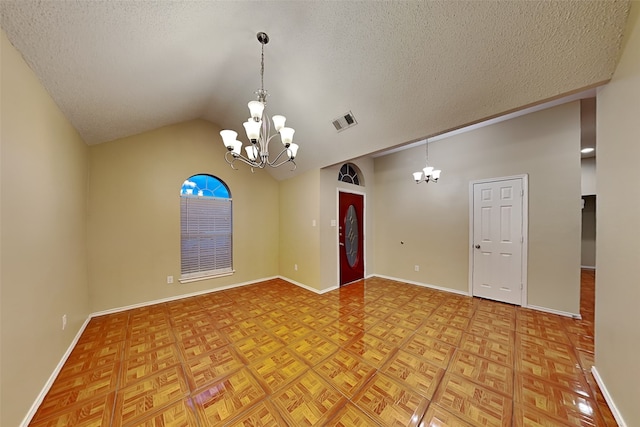 spare room featuring lofted ceiling, a chandelier, and a textured ceiling