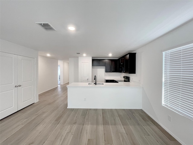 kitchen featuring light hardwood / wood-style floors, kitchen peninsula, plenty of natural light, stove, and sink