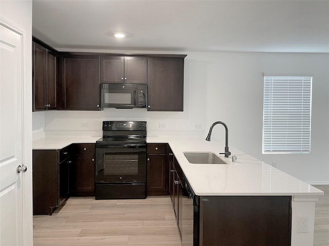 kitchen with kitchen peninsula, black appliances, light hardwood / wood-style flooring, dark brown cabinetry, and sink