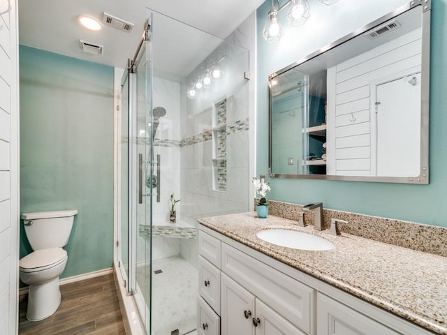 bathroom with a shower with shower door, toilet, and vanity