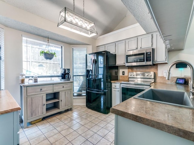 kitchen featuring pendant lighting, stainless steel appliances, sink, vaulted ceiling, and gray cabinetry