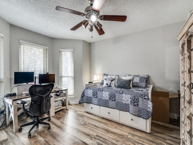 bedroom featuring ceiling fan, wood-type flooring, and a textured ceiling