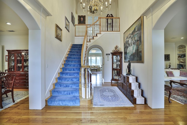 foyer featuring hardwood / wood-style floors, ornamental molding, a chandelier, and a high ceiling