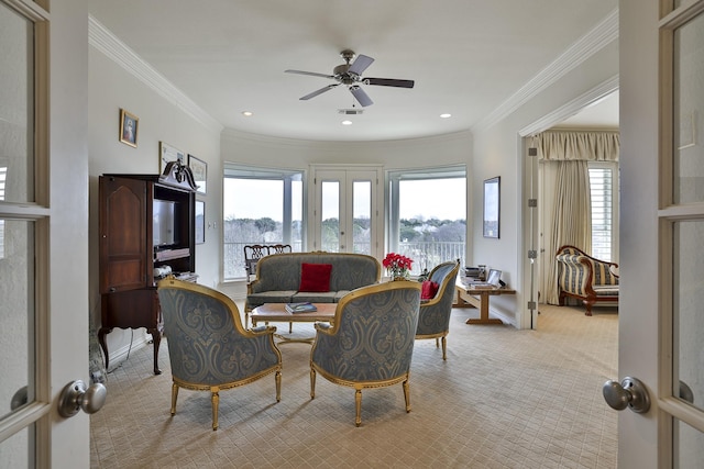 carpeted living room with crown molding, ceiling fan, and french doors