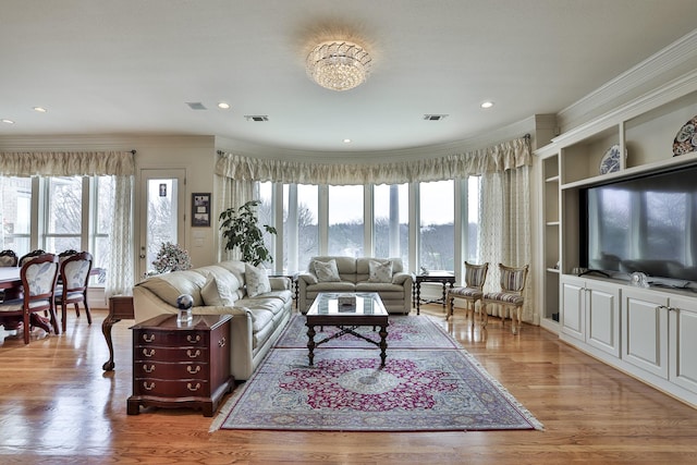 living room featuring wood-type flooring, ornamental molding, and a healthy amount of sunlight