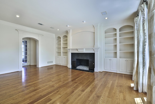 6601 Oak Hill Ct, Fort Worth, TX 76132 - unfurnished living room with built in features, wood finished floors, arched walkways, a tiled fireplace, and baseboards