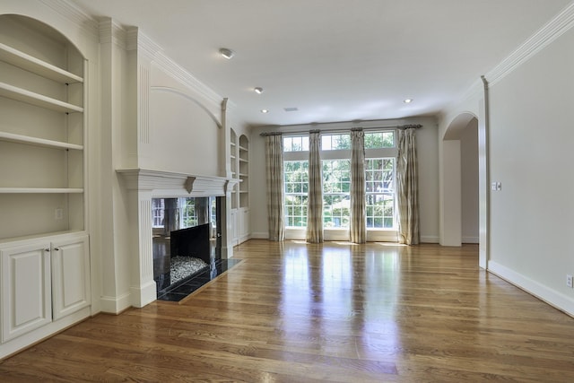 6601 Oak Hill Ct, Fort Worth, TX 76132 - unfurnished living room with built in shelves, arched walkways, wood finished floors, a high end fireplace, and recessed lighting