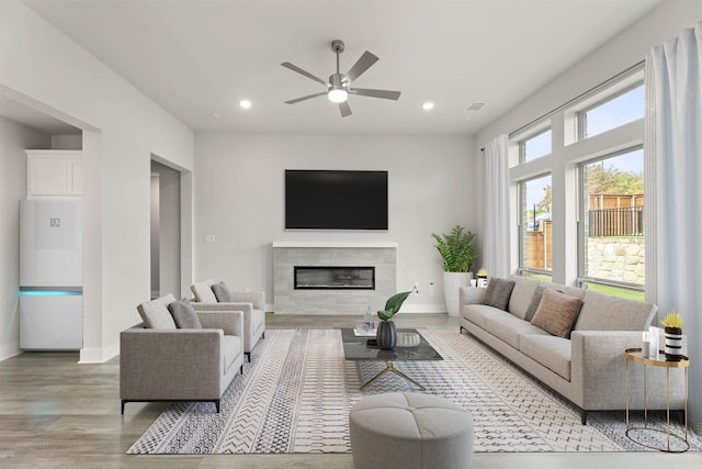 living room with ceiling fan, a tile fireplace, and light hardwood / wood-style flooring