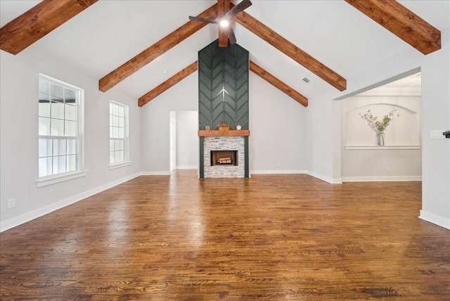 unfurnished living room with dark wood-type flooring, beam ceiling, and a fireplace