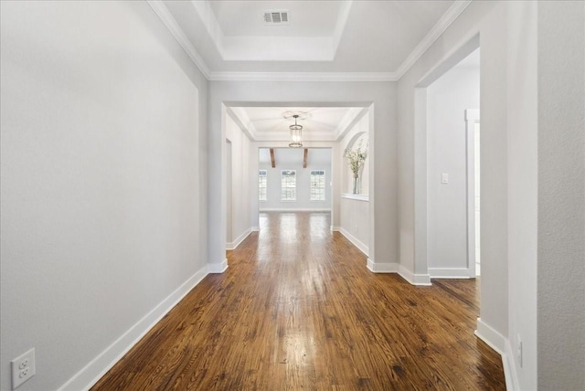 hallway with dark wood-type flooring, crown molding, and a tray ceiling