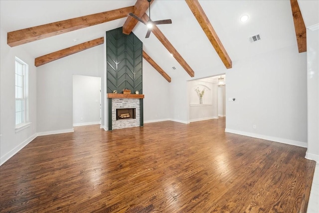 unfurnished living room featuring dark wood-type flooring, a stone fireplace, ceiling fan, high vaulted ceiling, and beam ceiling