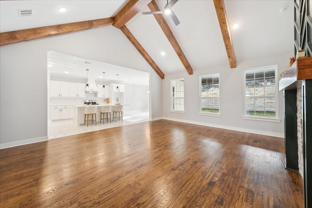 unfurnished living room with ceiling fan, hardwood / wood-style flooring, high vaulted ceiling, and beamed ceiling