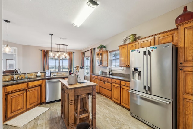 kitchen with stainless steel appliances, pendant lighting, light hardwood / wood-style flooring, and sink