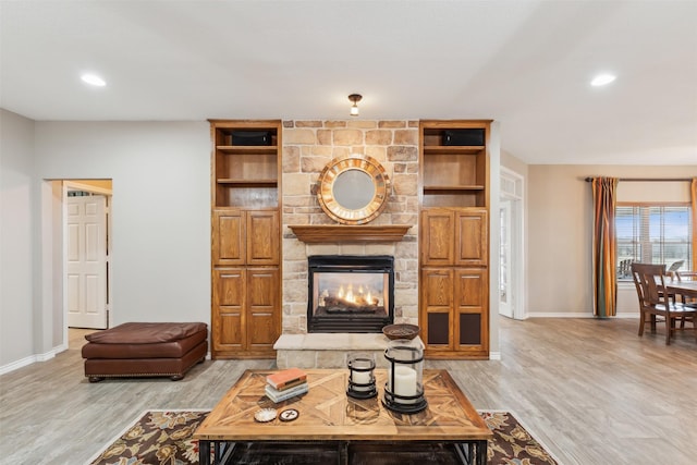 living room with light hardwood / wood-style flooring and a stone fireplace