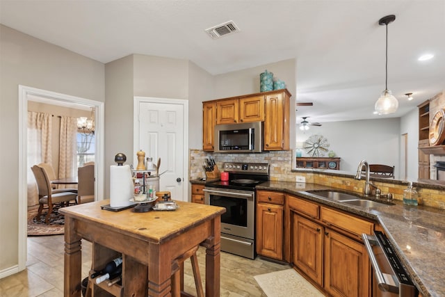 kitchen with decorative light fixtures, decorative backsplash, sink, appliances with stainless steel finishes, and dark stone counters