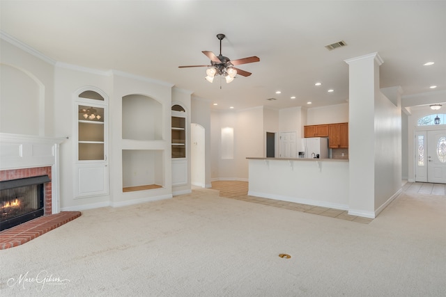 unfurnished living room featuring light carpet, ornamental molding, a fireplace, and built in shelves