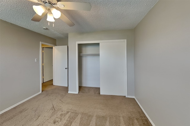 unfurnished bedroom featuring ceiling fan, light colored carpet, a textured ceiling, and a closet