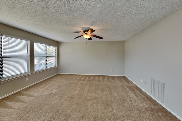 spare room with ceiling fan, a textured ceiling, and light carpet