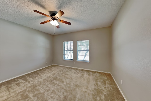 empty room featuring ceiling fan, light colored carpet, and a textured ceiling