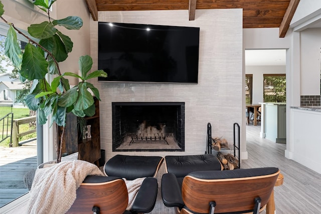 living room with wooden ceiling, lofted ceiling with beams, a fireplace, and light hardwood / wood-style floors