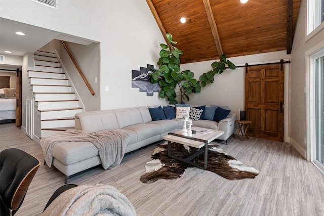 living room featuring light wood-type flooring, wood ceiling, a barn door, and high vaulted ceiling