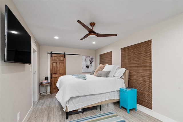 bedroom with ceiling fan, hardwood / wood-style flooring, and a barn door