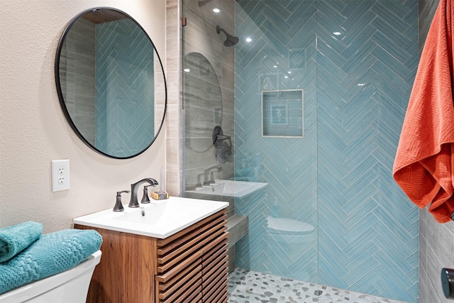 bathroom featuring toilet, vanity, and tiled shower