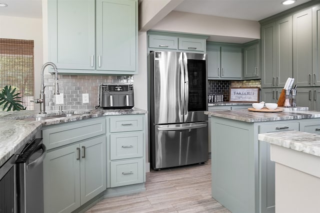 kitchen featuring stainless steel appliances, backsplash, and light stone countertops