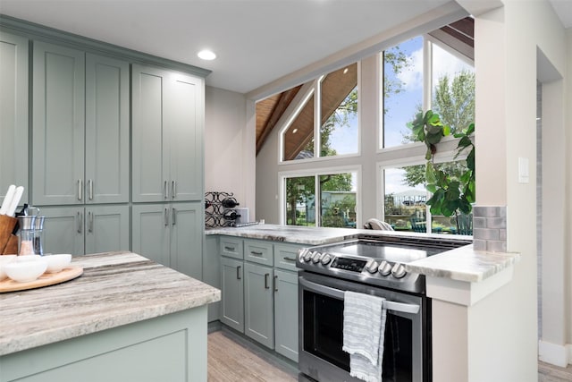 kitchen with tasteful backsplash, stainless steel electric range, light stone counters, and light hardwood / wood-style flooring