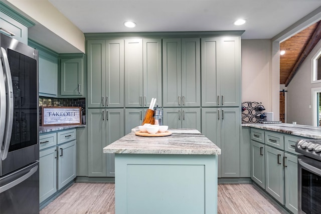 kitchen featuring green cabinets, appliances with stainless steel finishes, decorative backsplash, light stone countertops, and a center island