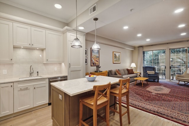 kitchen featuring decorative light fixtures, stainless steel dishwasher, a breakfast bar, decorative backsplash, and sink